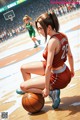 A woman kneeling on a basketball court with a ball in her hand.