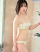 A woman in a yellow bikini standing in a shower.