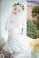 A woman in a wedding dress sitting on a window sill.