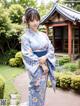 A woman in a blue kimono standing in front of a building.