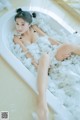 A woman laying in a bathtub filled with foam.