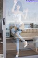 A woman in a white bodysuit and high heels standing in front of a glass door.