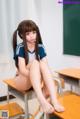 A young woman sitting on a desk in a classroom.