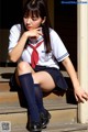 A woman in a school uniform sitting on some steps.