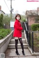 A woman in a red coat and black stockings posing for a picture.