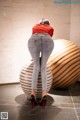 A woman in a red shirt and jeans is standing on a ball.