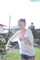 A woman is playing with a hose in the grass.