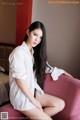 A woman sitting on a red chair in a hotel room.