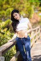 A woman in a white top and blue jeans posing on a wooden bridge.