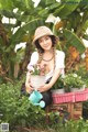 A woman sitting in a garden holding a watering can.