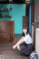 A woman in a school uniform crouching on a wooden floor.