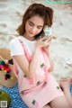 A woman sitting on a beach holding a shell.