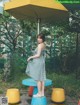 A woman in a blue and white dress standing under an umbrella.