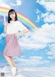 A woman in a white shirt and pink skirt holding a rainbow.