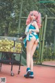 A woman with pink hair standing next to a cart of tennis balls.